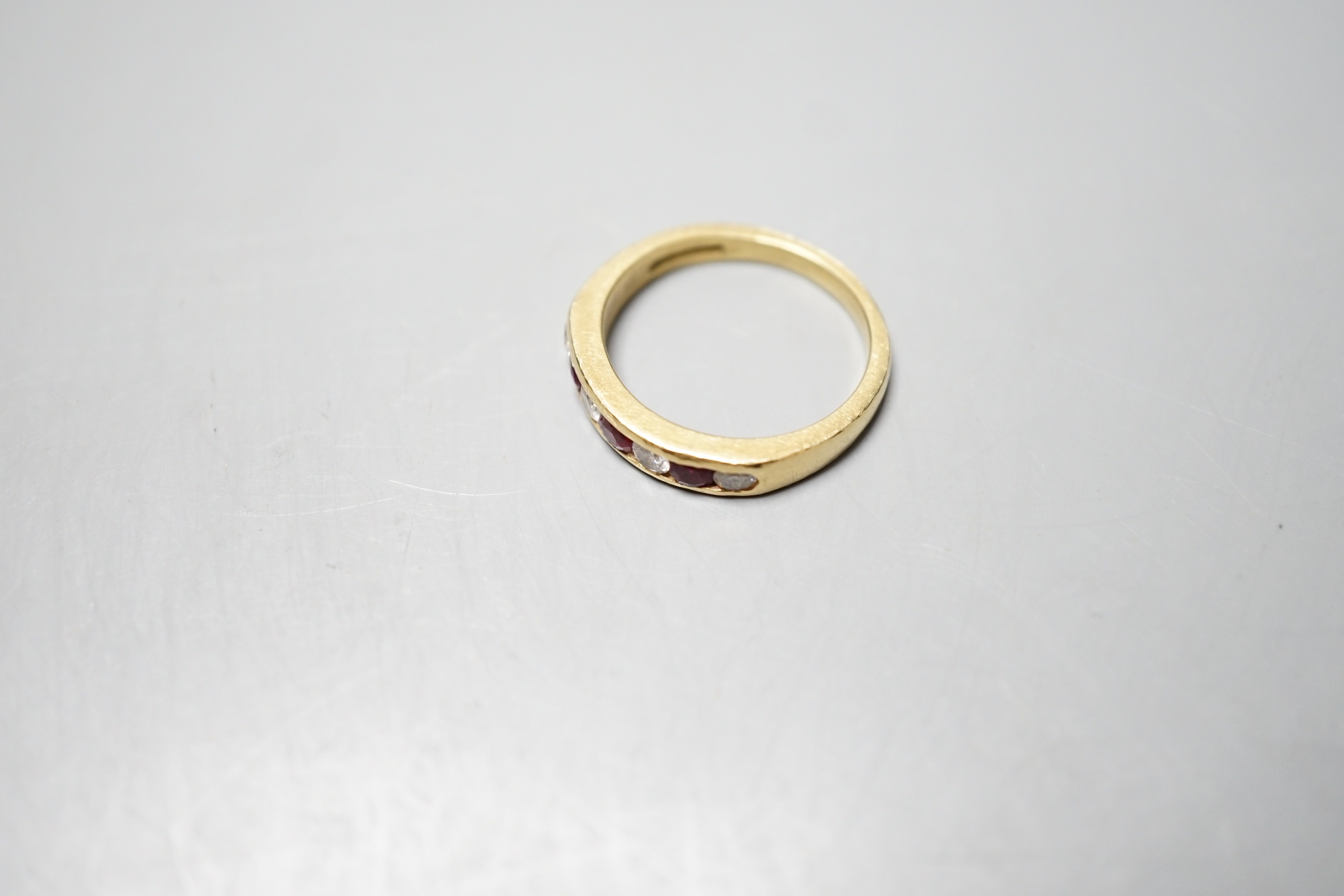 A modern 18ct gold and channel set four stone diamond and three stone ruby set half hoop ring, size N, gross weight 4.3 grams.